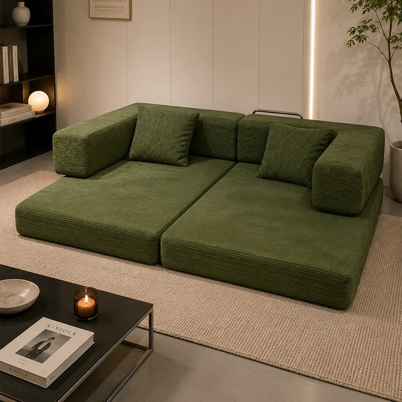 Green corduroy boneless sofa bed opened flat into a guest bed on a rug — Green